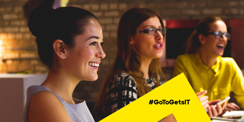 Three professionals smiling and laughing together in a meeting, representing the partnership benefit of IT vendor consolidation