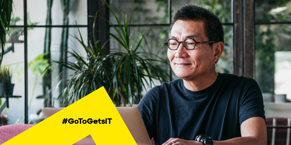 Homem em uma sala cheia de plantas e trabalhando em um notebook para aprender a resolver erros de DNS